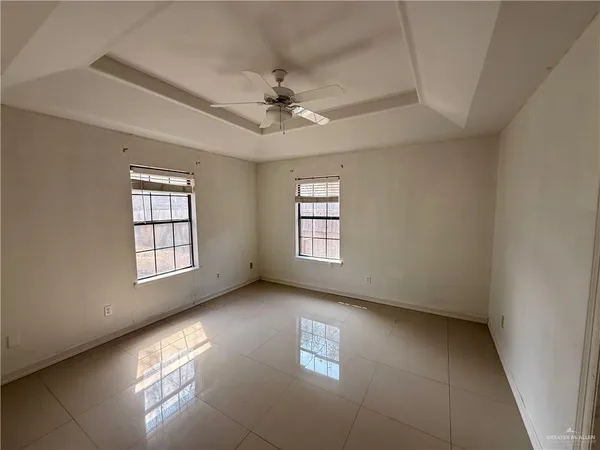 an empty room with windows and ceiling fan
