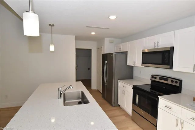 a kitchen with a sink a microwave a refrigerator and cabinets