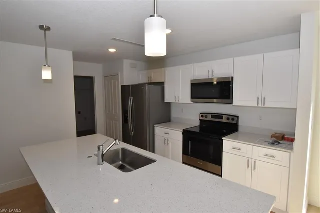 a kitchen with stainless steel appliances granite countertop a refrigerator a stove a sink and a microwave