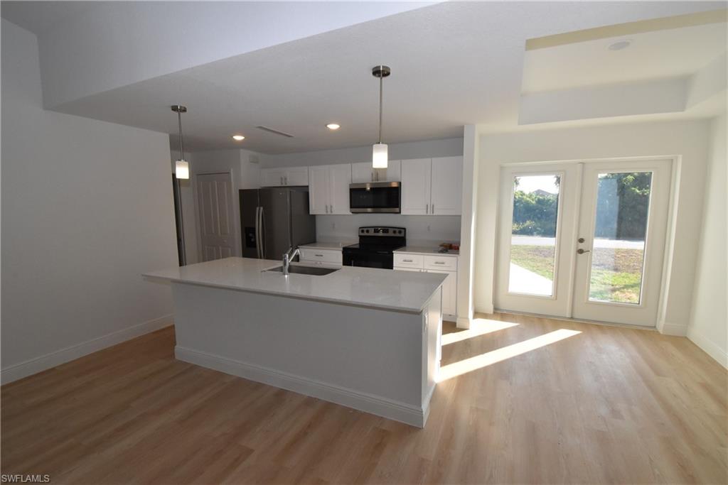5051 Foxhall Road North Port, FL 34288 - Photo 4 of 27 a large kitchen with kitchen island a sink dishwasher stove and white cabinets with wooden floor