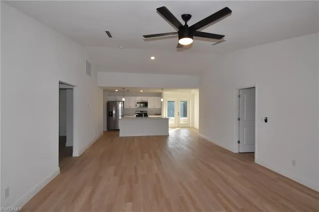 a view of a hallway with wooden floor and a kitchen space with a sink