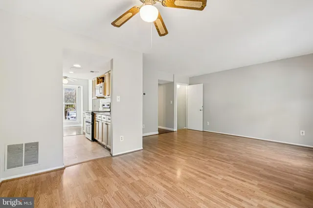 a view of an empty room with wooden floor and a window