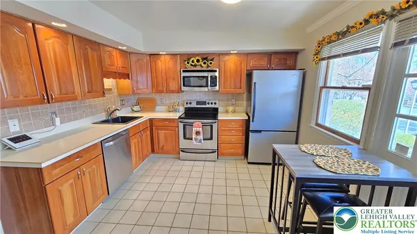 a kitchen with stainless steel appliances a stove top oven refrigerator a sink dishwasher and wooden cabinets