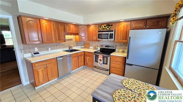 a kitchen with stainless steel appliances granite countertop a refrigerator sink and wooden cabinets