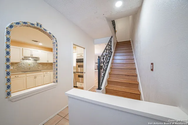 a view of a hallway with granite countertop a fireplace and a chandelier
