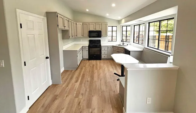 a kitchen with kitchen island wooden floors white cabinets and stainless steel appliances