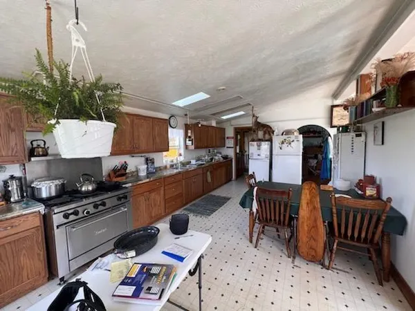 a kitchen with stainless steel appliances kitchen island granite countertop a table chairs in it and wooden floors