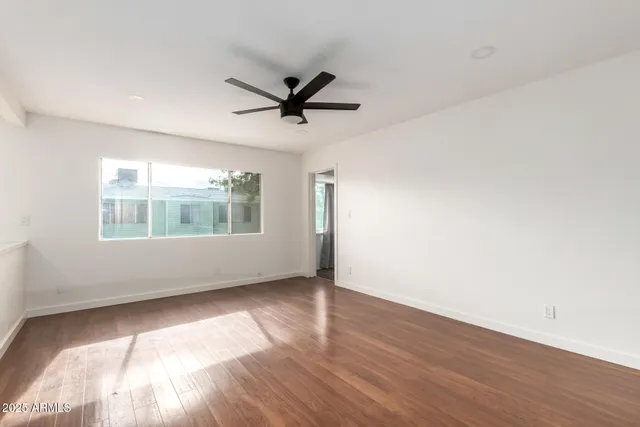 a view of an empty room with wooden floor and a window