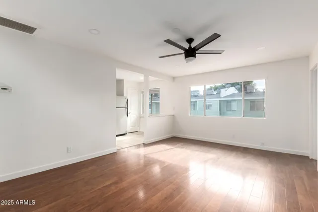 a view of an empty room with a window and wooden floor