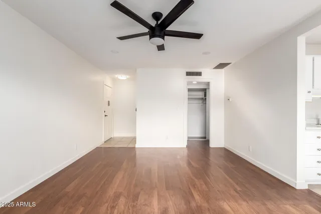 a view of empty room with wooden floor and ceiling fan