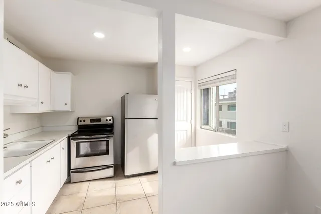 a kitchen with white cabinets and refrigerator