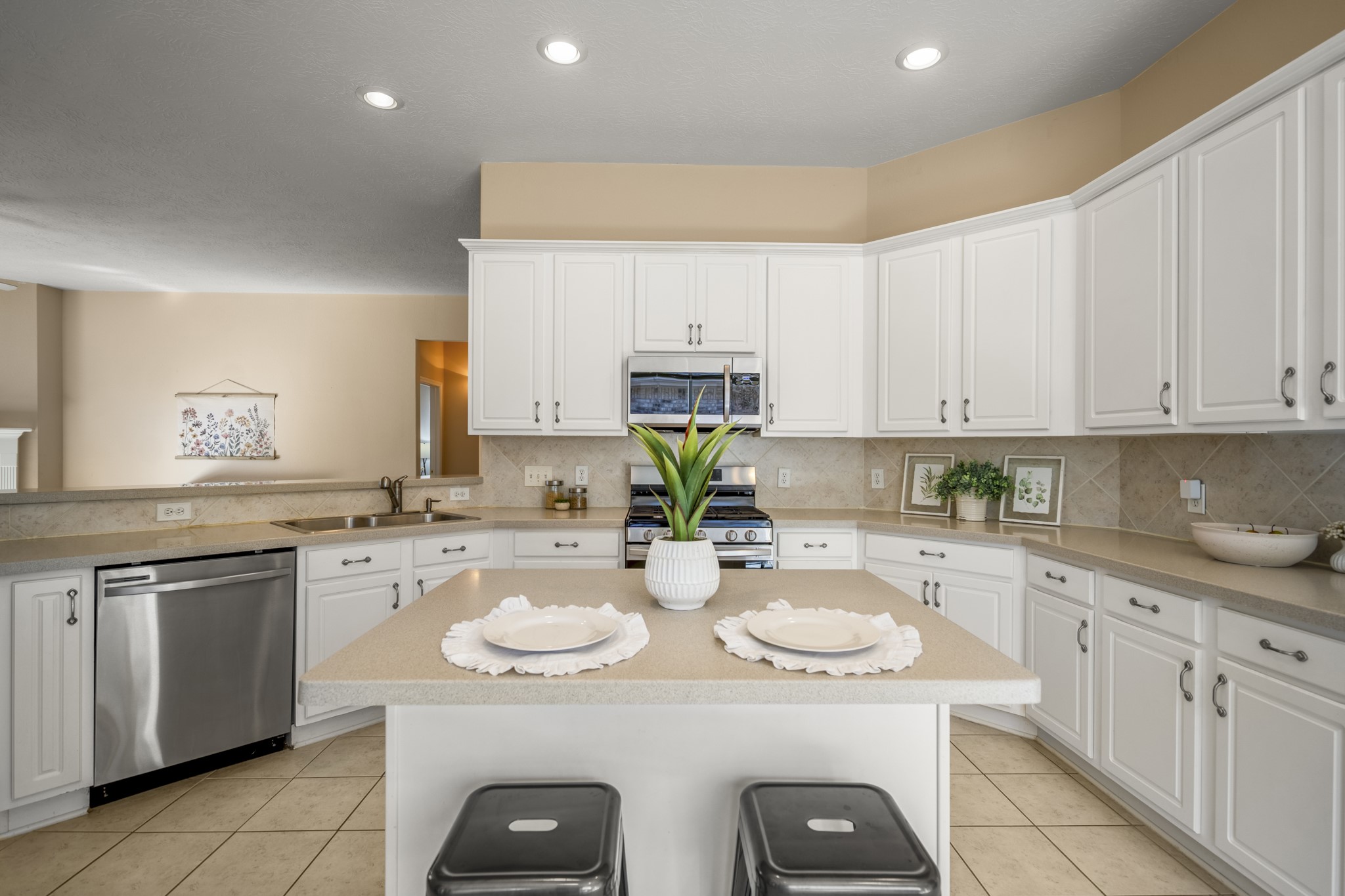 21107 Coldde Meadow Lane Spring, TX 77379 - Photo 12 of 50 Here, the kitchen’s main work area comes into focus with Corian countertops, stainless steel appliances, and a gas range ready for everyday cooking. The island provides additional prep space and casual seating, while the surrounding cabinetry keeps everything organized and within easy reach.