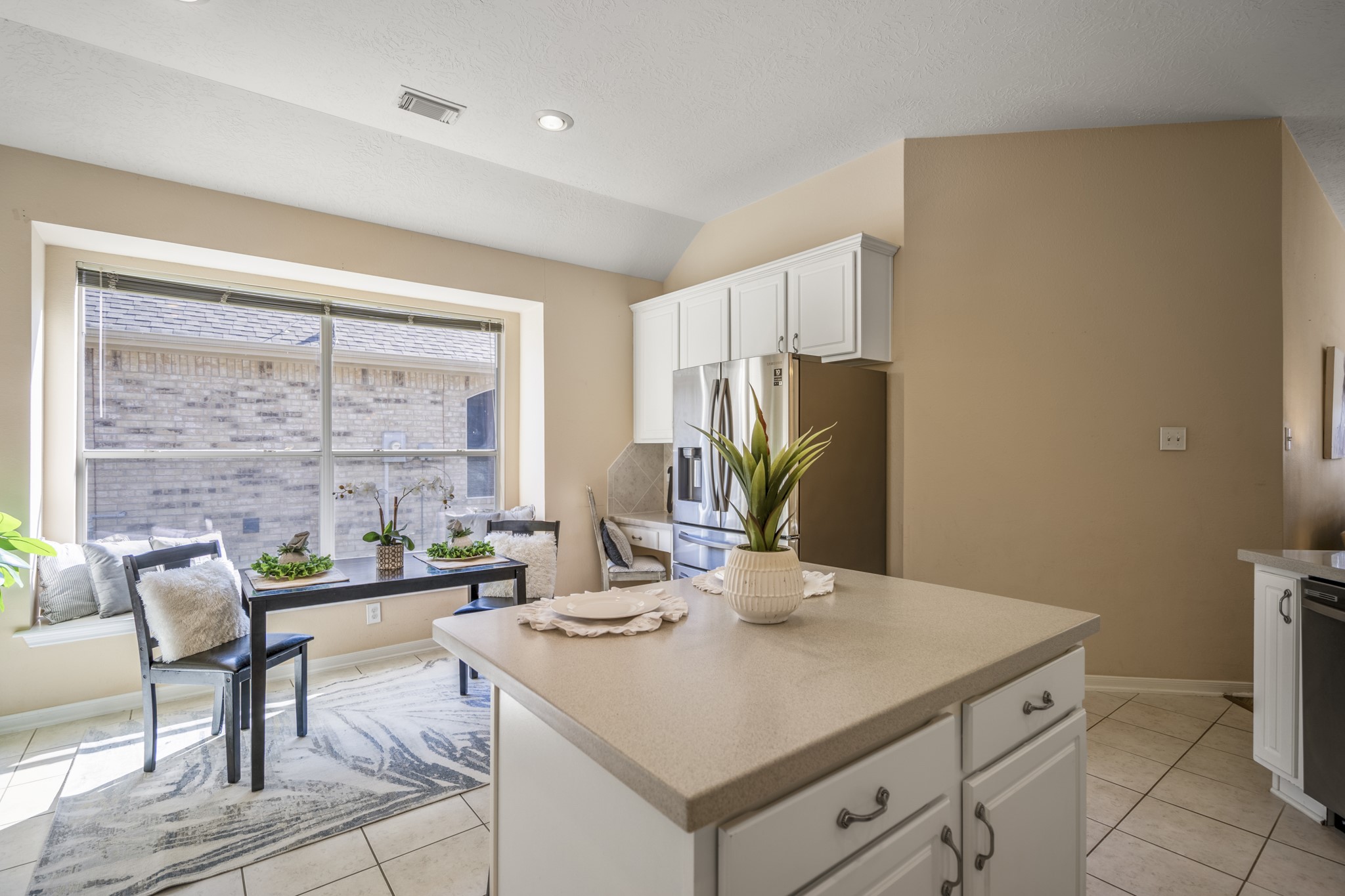 21107 Coldde Meadow Lane Spring, TX 77379 - Photo 14 of 50 Continuing around the island, the view opens to the breakfast area where large windows bring in natural light and views of the backyard. A built in bench window seat adds charm and creates a cozy spot for morning coffee or casual meals. Just beyond, the refrigerator area and built in desk or coffee bar space add extra function for daily routines and staying organized.