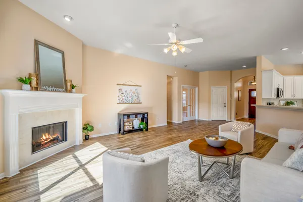 a kitchen with stainless steel appliances kitchen island granite countertop a refrigerator a stove a sink a dining table and chairs with wooden floor