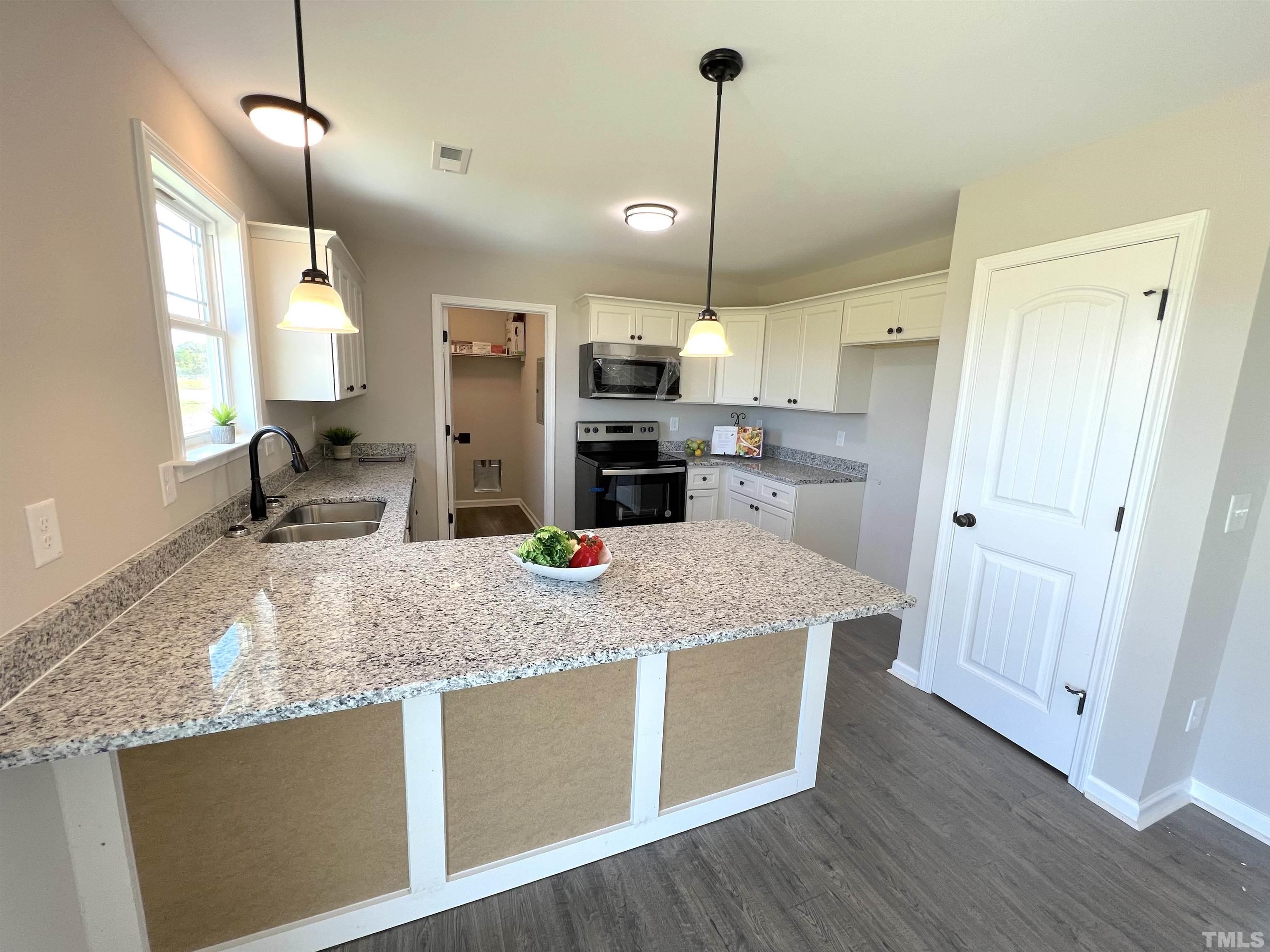 111 Adds Road Pikeville, NC 27863 - Photo 8 of 23 a kitchen with kitchen island a counter top space appliances and a ceiling fan