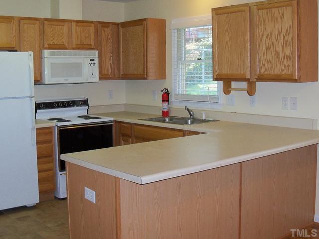 2124 Balboa Road Raleigh, NC 27603 - Photo 3 of 24 Spacious kitchen with ceramic tile floor, refrigerator, stove, microwave and dishwasher open to dining area.