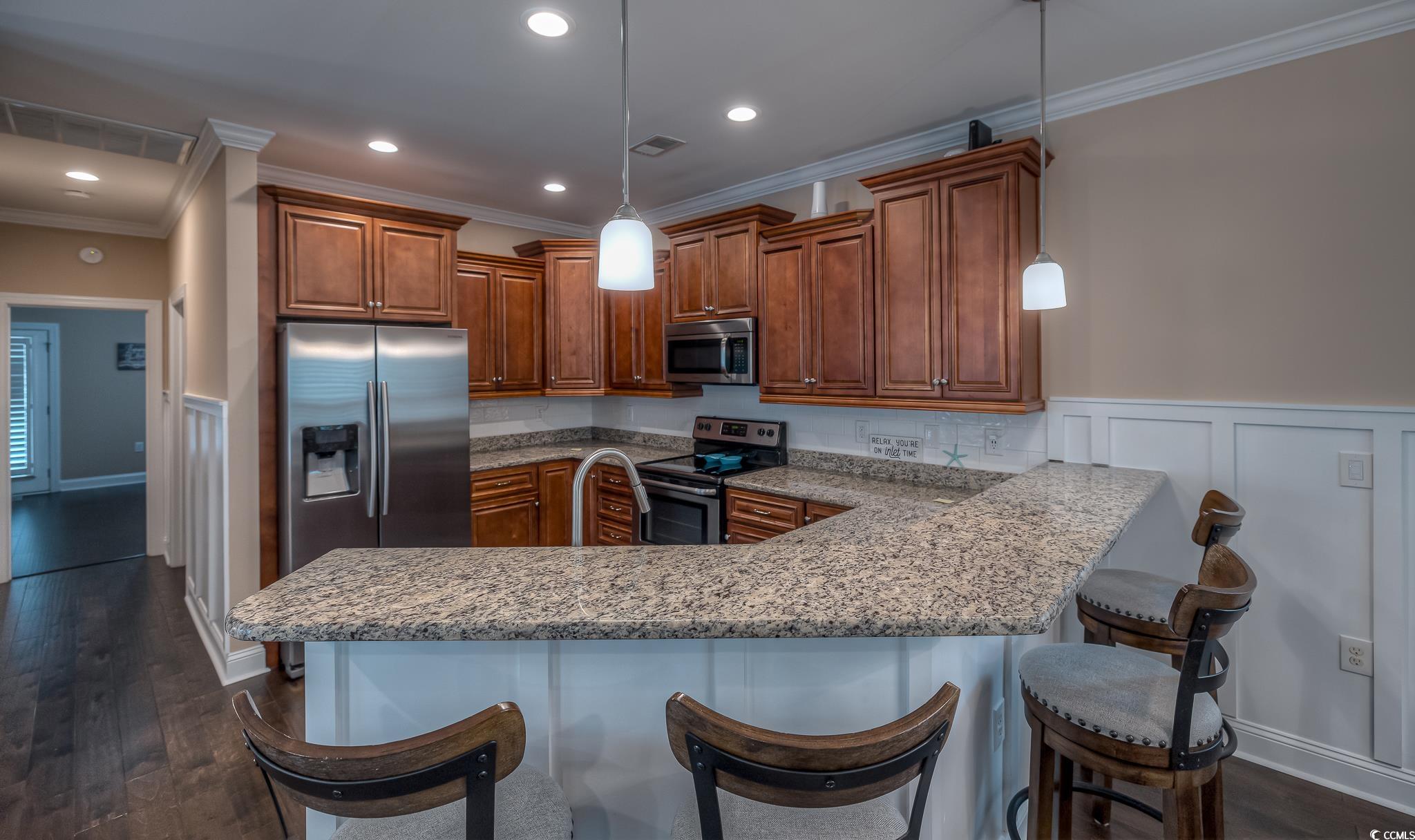 103 Charles Towne Lane Murrells Inlet, SC 29576 - Photo 11 of 23 Kitchen featuring a decorative wall, wainscoting, crown molding, stainless steel appliances, and a peninsula