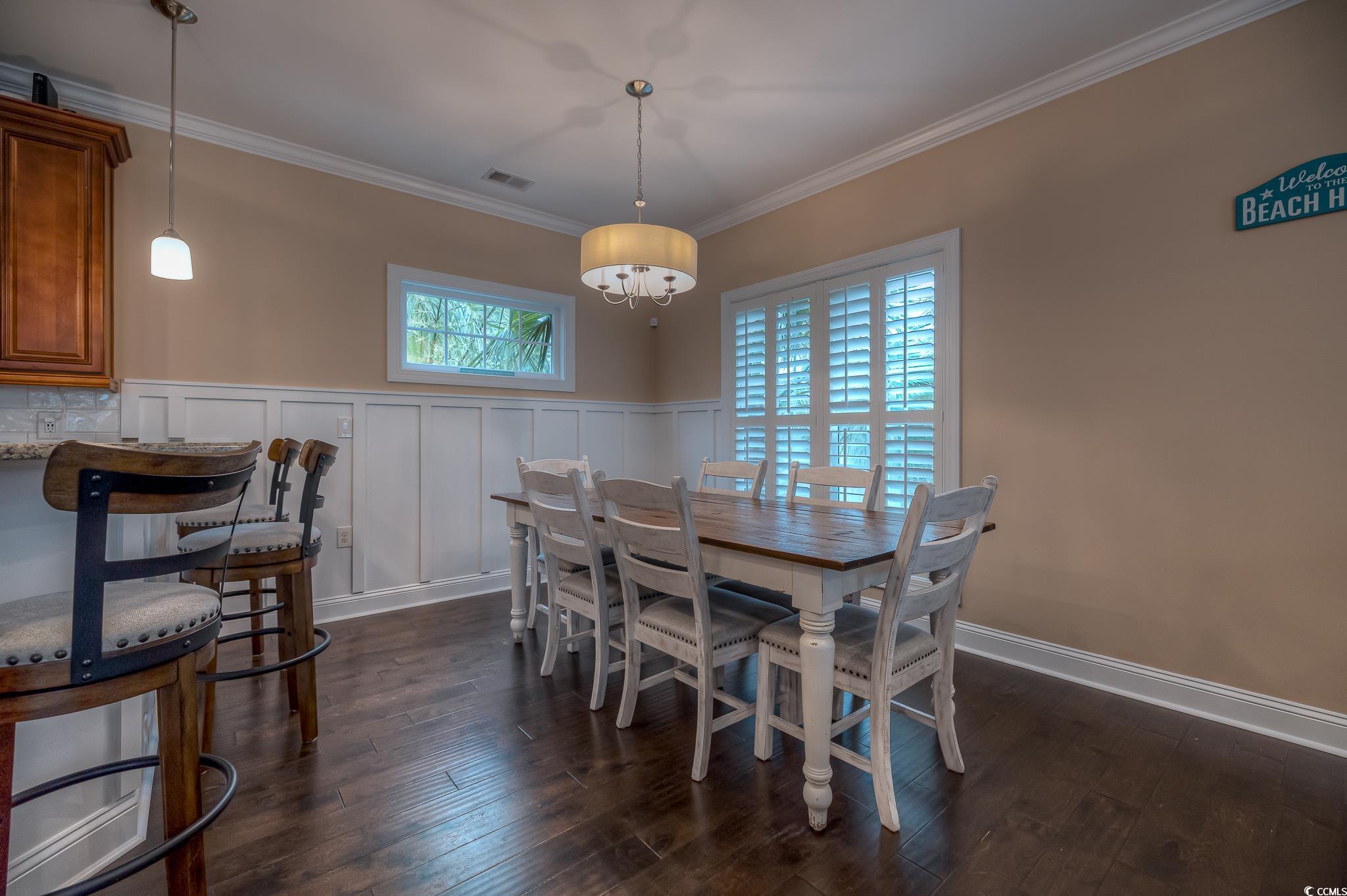 103 Charles Towne Lane Murrells Inlet, SC 29576 - Photo 9 of 23 Dining area with crown molding, dark wood-type flooring, a decorative wall, and wainscoting