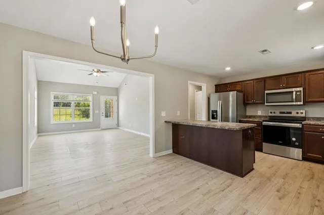 a large kitchen with stainless steel appliances granite countertop a stove and a wooden floors