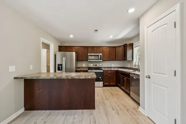 a kitchen with stainless steel appliances granite countertop a stove a sink and a refrigerator