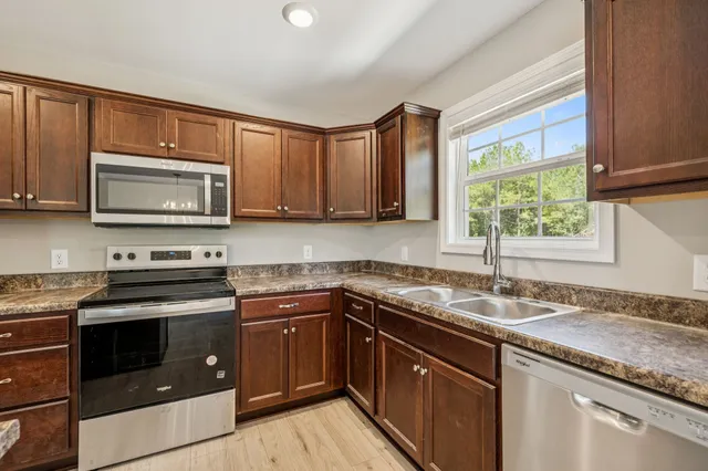 a kitchen with granite countertop a sink stove and microwave