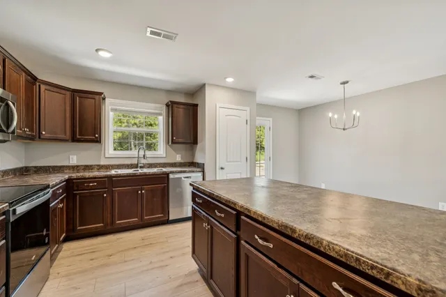 a kitchen with stainless steel appliances granite countertop a sink stove and cabinets