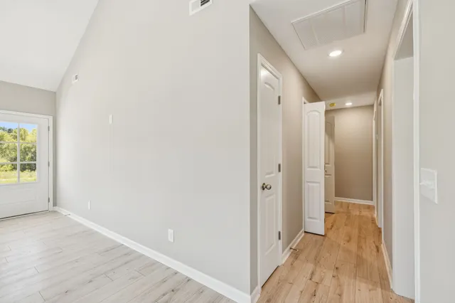 a view of a hallway with wooden floor and a bathroom