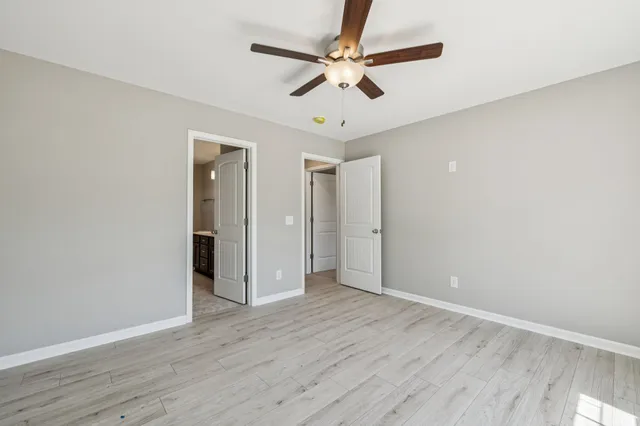 an empty room with wooden floor fan and windows