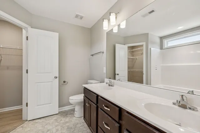 a bathroom with a double vanity sink mirror and toilet