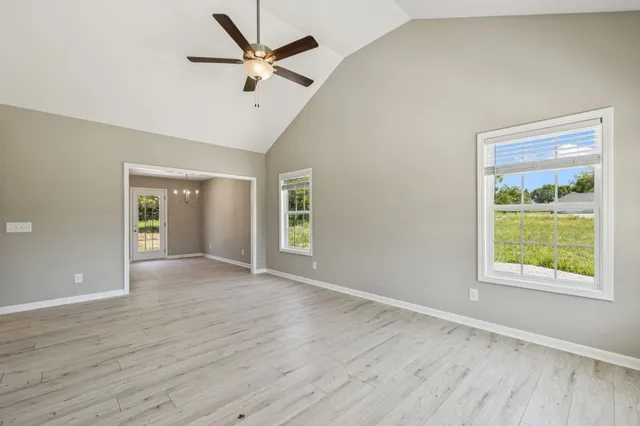 a view of an empty room with a window and wooden floor