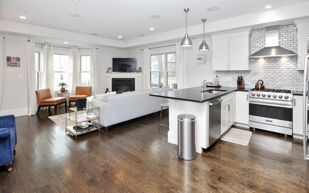 a kitchen with kitchen island granite countertop a stove and a wooden floor
