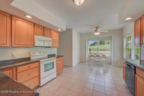 a kitchen with stainless steel appliances kitchen island granite countertop a dining table chairs and a large window