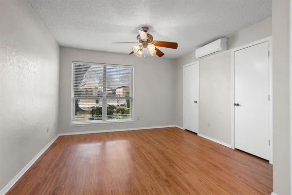 a view of empty room with wooden floor and fan
