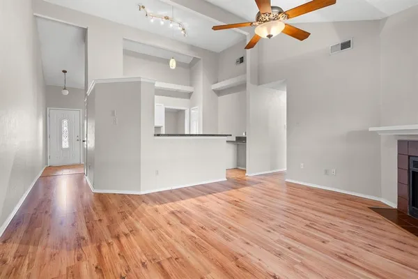 a view of empty room with wooden floor and fan