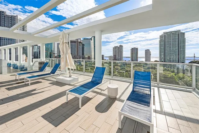 a view of a dining room with furniture a chandelier and large windows