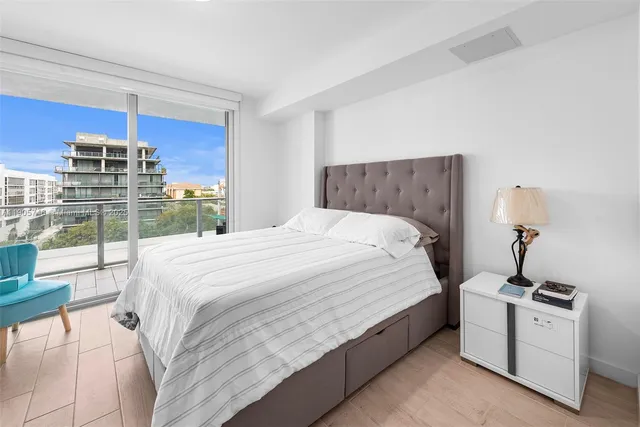 a large white bed in a bedroom next to a window