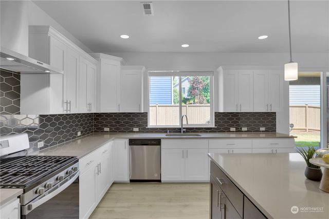 a kitchen with stainless steel appliances granite countertop a sink stove and cabinets