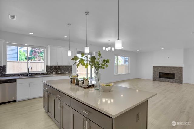 a kitchen with kitchen island granite countertop a sink cabinets and stainless steel appliances
