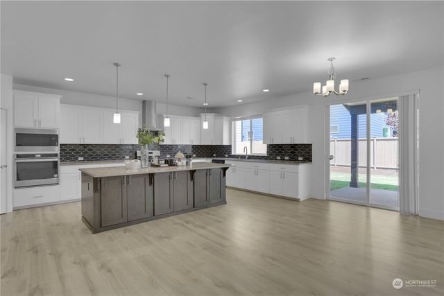 a large white kitchen with kitchen island a sink stainless steel appliances and cabinets