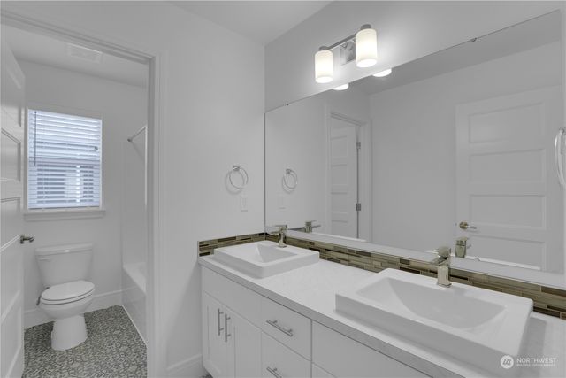 a bathroom with a granite countertop sink a toilet and a mirror