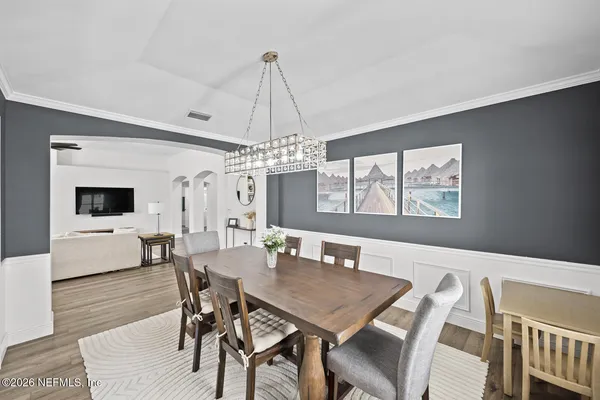 a view of a dining room with furniture a chandelier and wooden floor