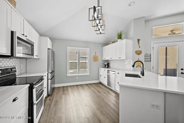 a kitchen with stainless steel appliances granite countertop a stove top oven a sink dishwasher and a microwave with wooden floor