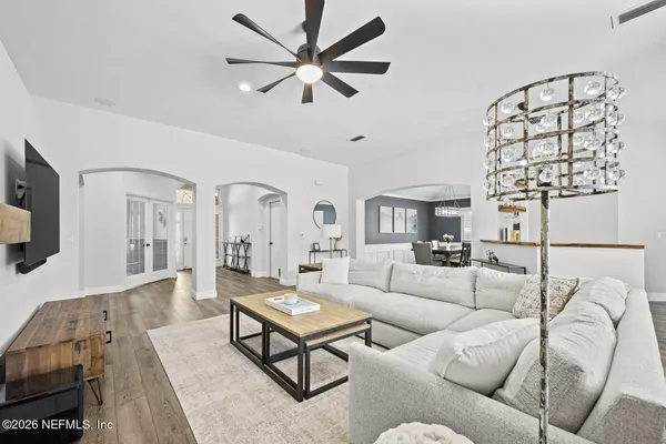 a living room with furniture a flat screen tv and a chandelier