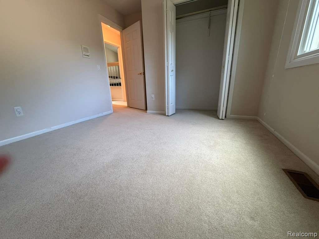 1154 Bluebird Drive Rochester, MI 48307 - Photo 19 of 34 Carpeted room featuring a white baseboard trim, a window with white casing, a closet with bi-fold doors, and a wall vent
