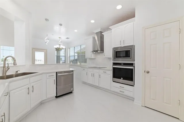 a large white kitchen with stainless steel appliances and white cabinets