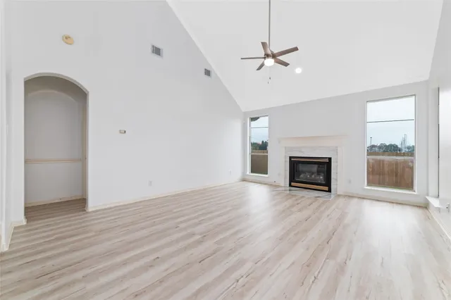 an empty room with wooden floor fireplace and windows