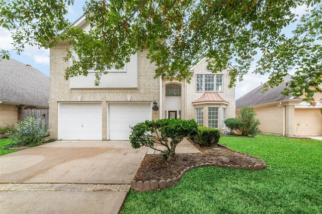 a front view of a house with a garden and a tree