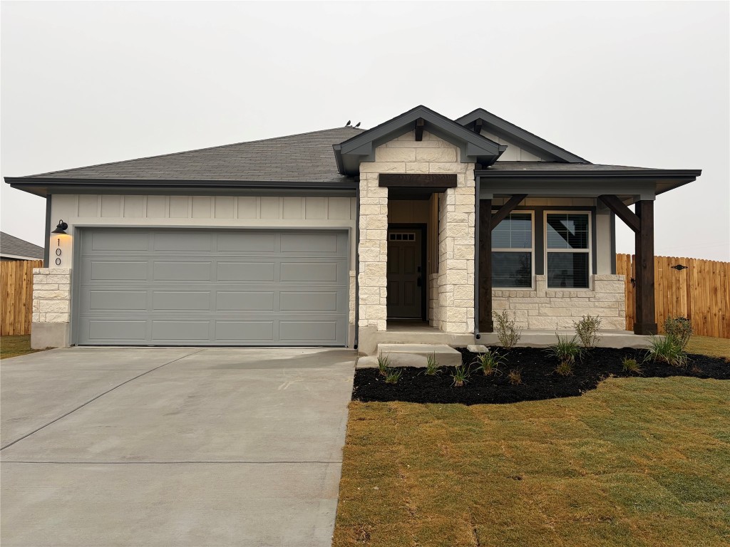 100 Honey Bee Road Jarrell, TX 76537 - Photo 1 of 17 View of front facade featuring stone siding, concrete driveway, a shingled roof, covered porch, and a garage