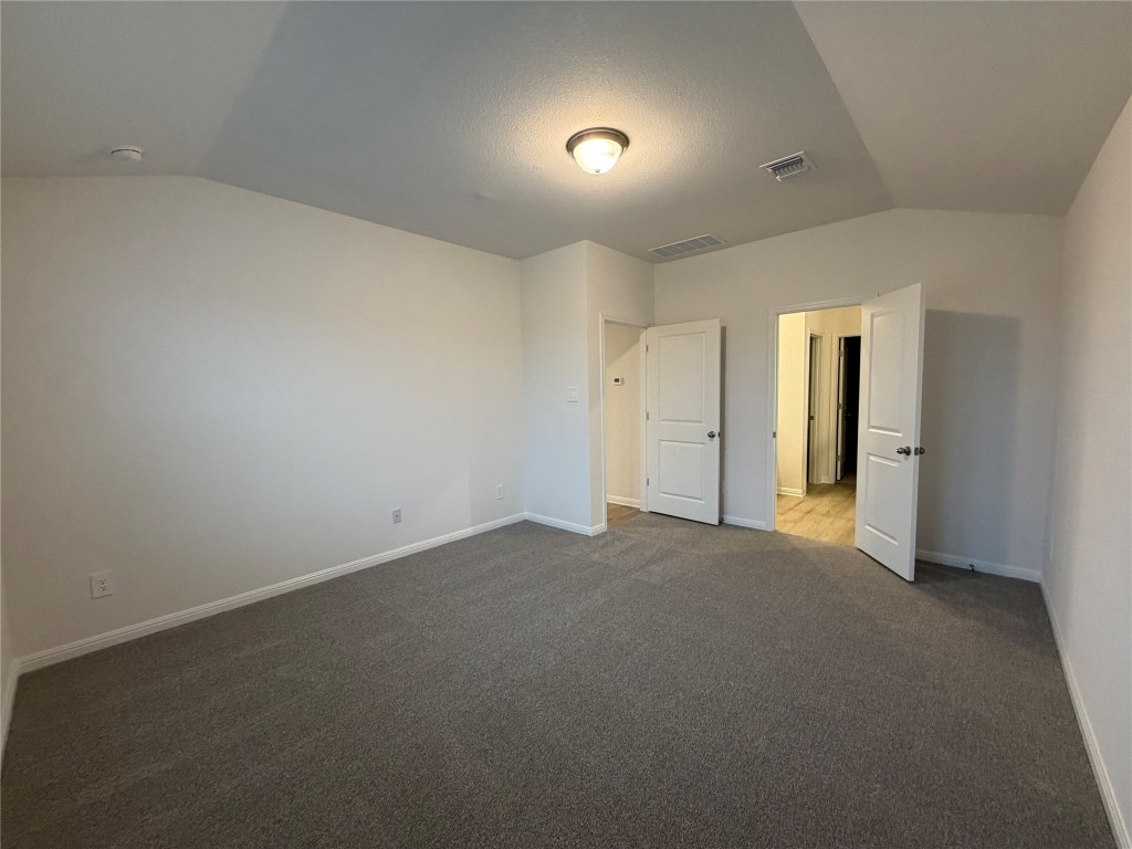 100 Honey Bee Road Jarrell, TX 76537 - Photo 3 of 17 Unfurnished bedroom featuring vaulted ceiling and dark colored carpet