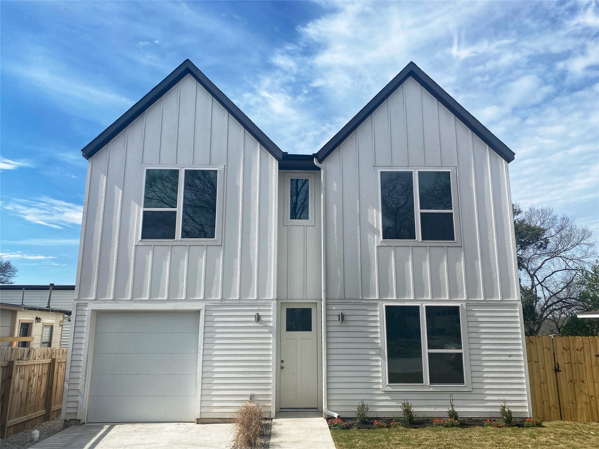 Modern two-story duplex featuring white vertical board-and-batten and horizontal siding